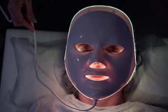 Karanlık bir odada, LED ışıkları yanan bir maske takan bir kişi.