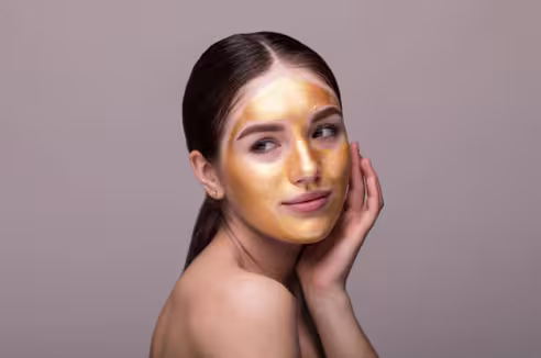 Yüzünde altın rengi bir maske ile poz veren genç bir kadın.